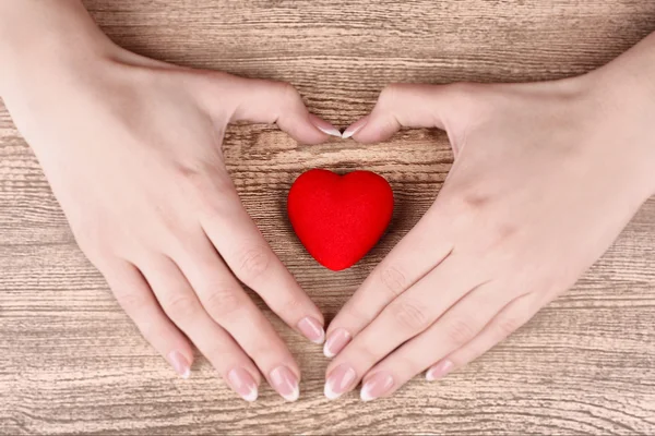 Rotes Herz in den Händen auf Holzgrund — Stockfoto