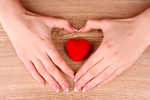 Red heart in hands on wooden background — Zdjęcie stockowe