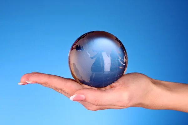 Кришталевий м'яч на руках. синій фон — стокове фото