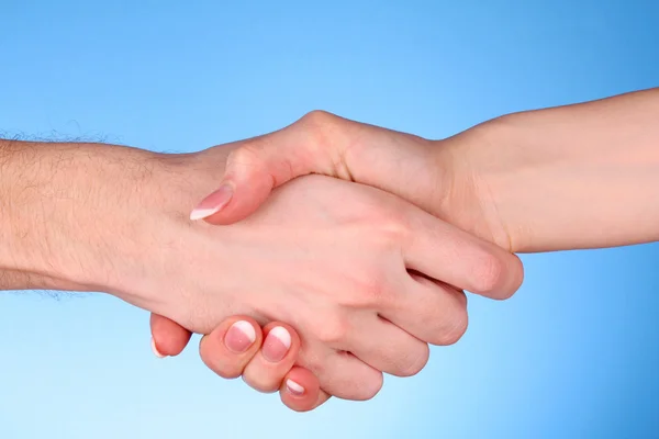 Handslag mellan man och kvinna på blå bakgrund — Stockfoto