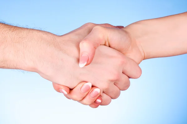 Kézfogás közötti férfi és nő a kék háttér — Stock Fotó