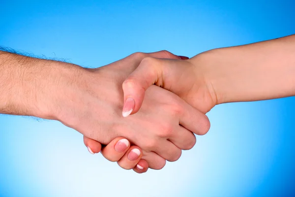 Handslag mellan man och kvinna på blå bakgrund — Stockfoto