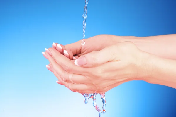 Ανθρώπινα χέρια με νερό πιτσίλισμα τους με μπλε φόντο — Φωτογραφία Αρχείου