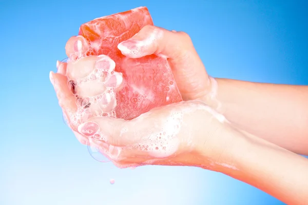 Handen met zeep op blauwe achtergrond — Stockfoto