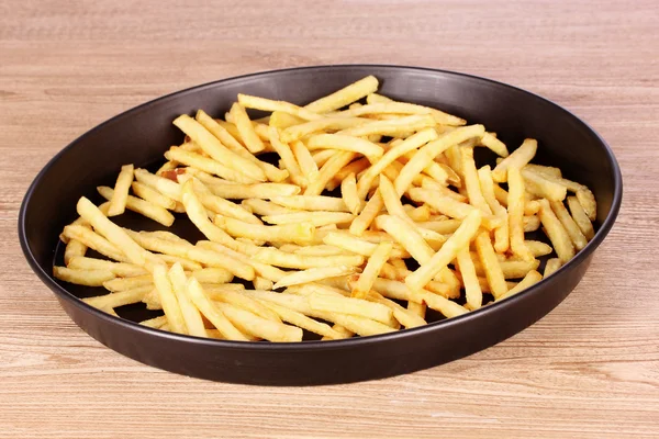 French fries in the pan on a wooden background — Stock Photo, Image