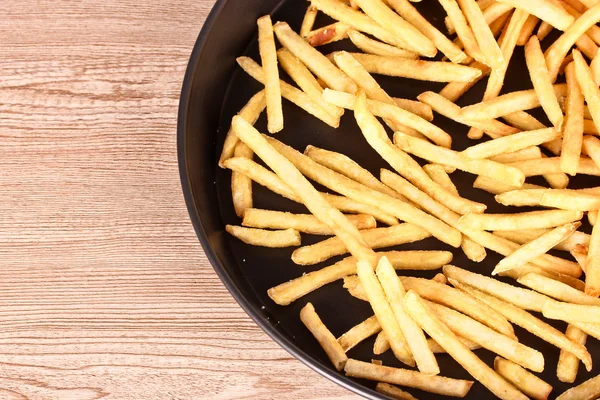Franse frietjes in de pan op een houten achtergrond — Stockfoto