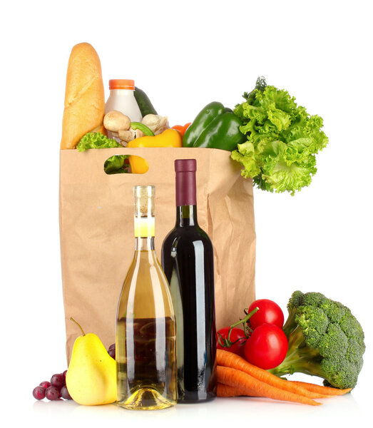 Vegetables in paper bag and wine bottles isolated on white