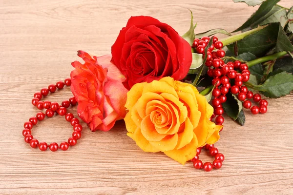 Drei Blumen und Perlen auf Holztisch — Stockfoto