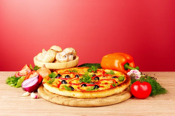 Pizza and vegetables on red background — Stock Photo, Image