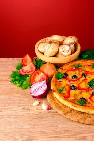 Pizza a zelenina na červeném pozadí — Stock fotografie
