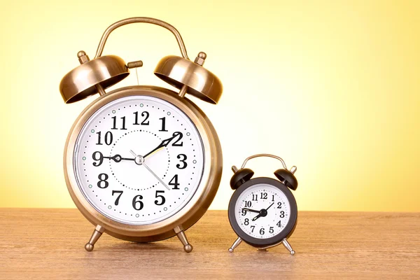 Two clocks with different time on yellow background — ストック写真