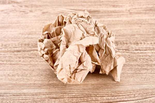 Bola de papel amassada marrom na textura de madeira — Fotografia de Stock