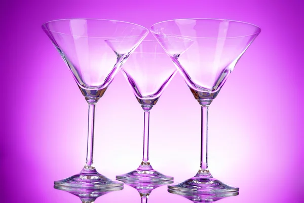 Três copos de martini vazios no fundo roxo — Fotografia de Stock