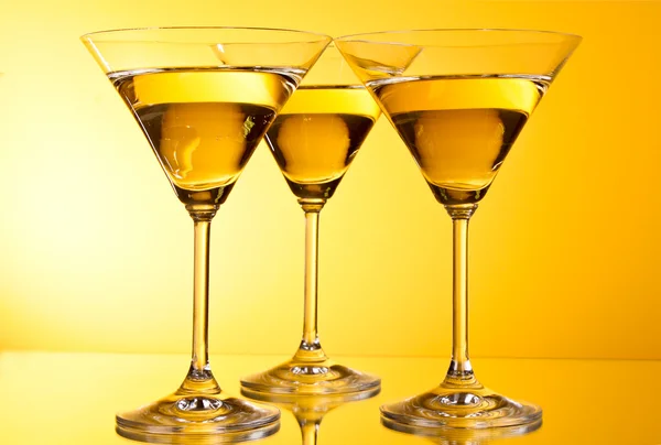 Three glasses of martini on a yellow background — Stock Photo, Image