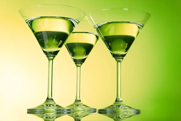 Trzy kieliszki dla martini na zielonym tle — Zdjęcie stockowe