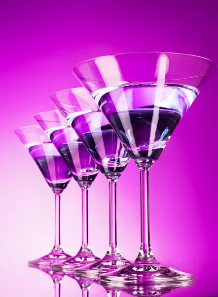 Cztery kieliszki dla martini na fioletowym tle — Zdjęcie stockowe
