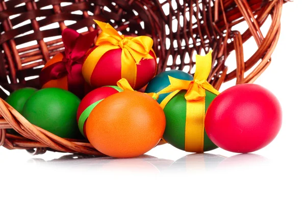 Wicker basket with Easter eggs isolated on white — Stock Photo, Image