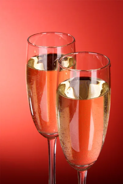 Dwa kieliszki szampana na czerwonym tle. — Zdjęcie stockowe