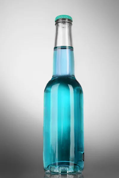 Bottiglia con alcol su sfondo grigio — Foto Stock