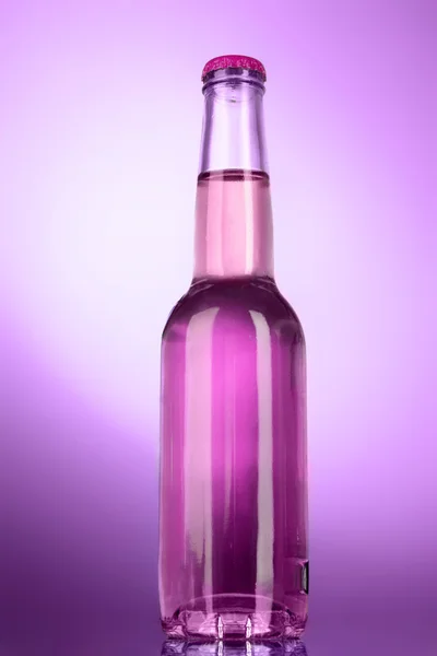 Láhev s alkoholem na fialovém pozadí — Stock fotografie