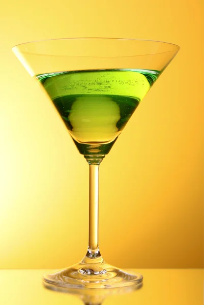 Γυαλί με ένα πράσινο οινοπνευματώδες ποτό, σε ένα φόντο κίτρινο-καφέ — Φωτογραφία Αρχείου