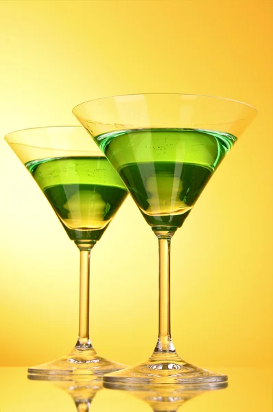 Vidrio con una bebida alcohólica verde a un fondo amarillo-marrón — Foto de Stock