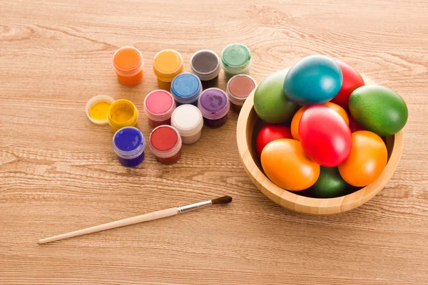 Colorido Easter Eggs, tintas e pincel na mesa de madeira — Fotografia de Stock