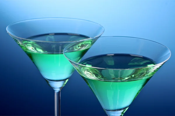 Two glasses of alcoholic beverage on a blue background — Stock Photo, Image