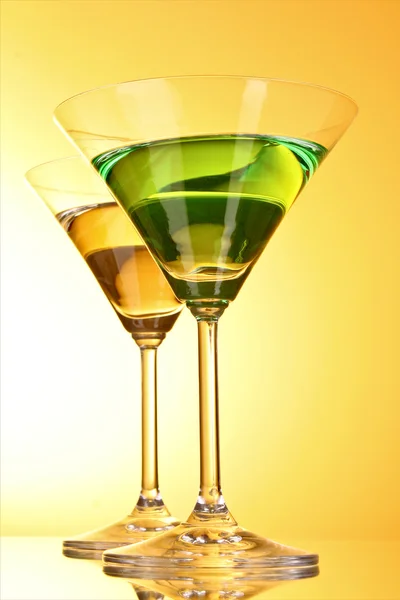Glas med en grön alkoholhaltig dryck till en gul-brun ba — Stockfoto
