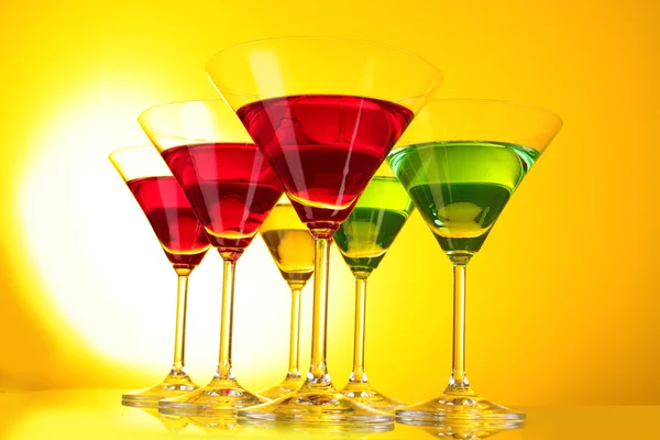 Några glas alkoholhaltiga drycker i en gul-brun bakgrund — Stockfoto