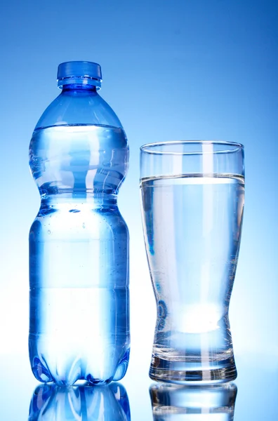 Garrafa de água e vidro sobre fundo azul — Fotografia de Stock