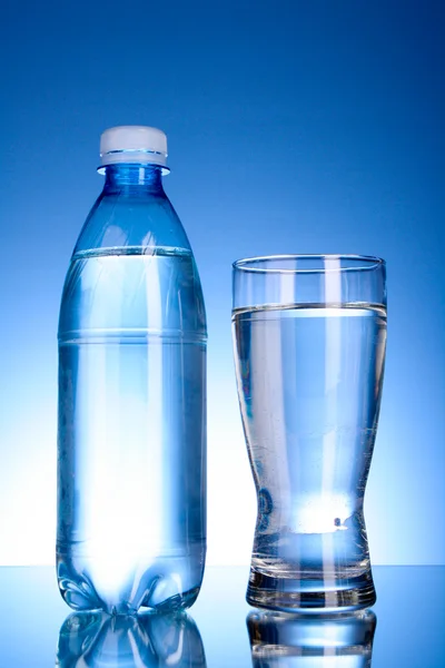 Fles water en glas op blauwe achtergrond — Stockfoto