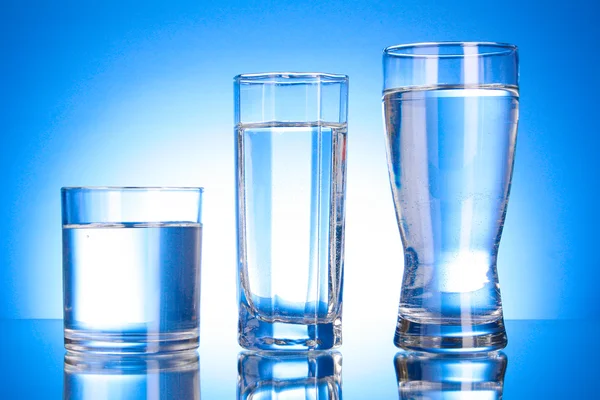 Tre bicchieri d'acqua su sfondo blu — Foto Stock