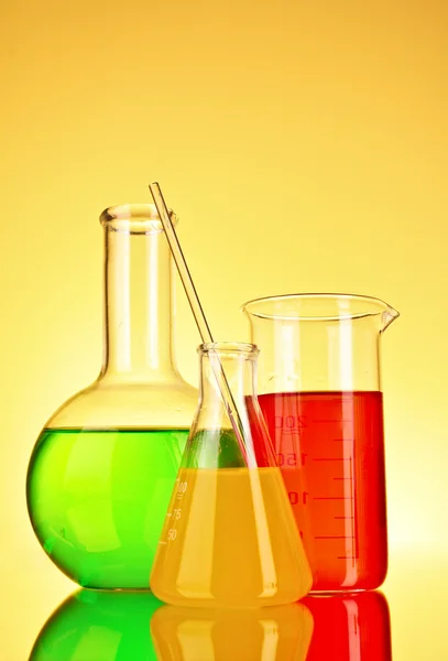 Laboratóriumi üvegeszközök, sárga háttér — Stock Fotó
