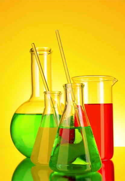 Laboratóriumi üvegeszközök, sárga háttér — Stock Fotó
