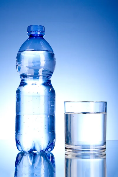 Botella de agua y vidrio sobre fondo azul —  Fotos de Stock