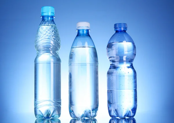 Flessen water op blauwe achtergrond — Stockfoto