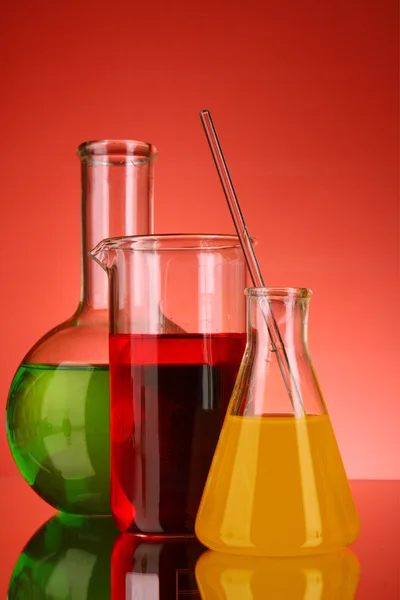 Laborgläser auf rotem Hintergrund — Stockfoto