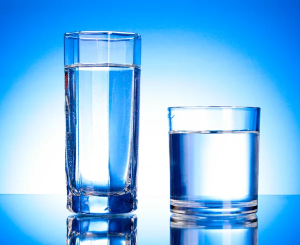 Два окуляри води на синьому фоні — стокове фото