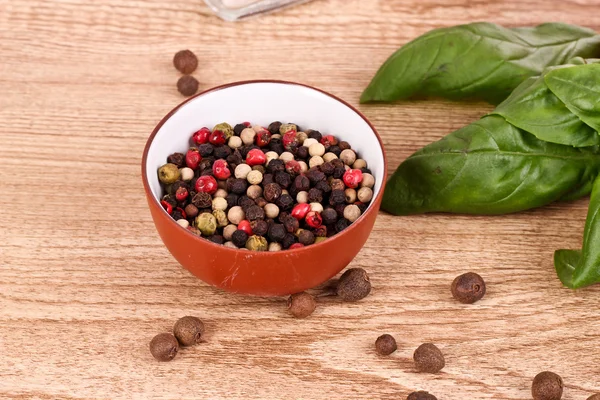 Pepper and basil on wooden table — Stock Photo, Image