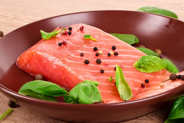 Peixe vermelho no prato com pimenta e folhas verdes — Fotografia de Stock