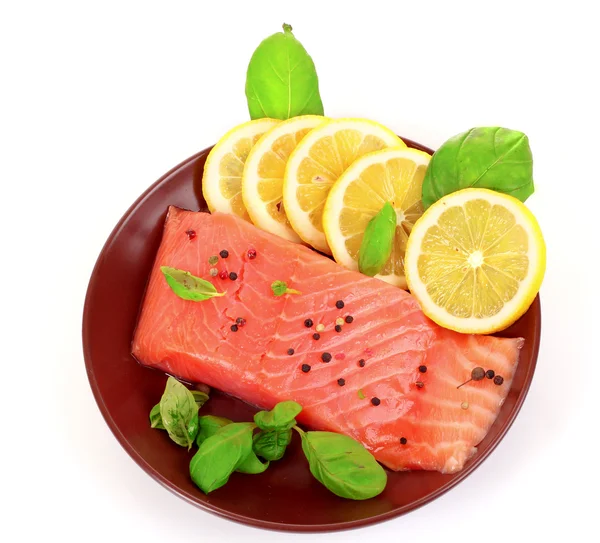 Красная рыба на тарелке с перцем и зелеными листьями — стоковое фото