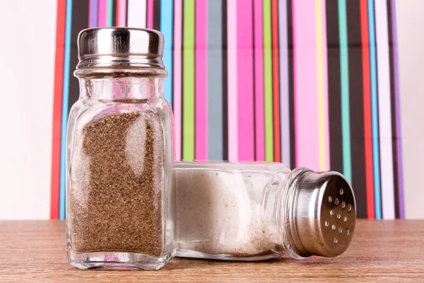 Salt och peppar shaker på färgad bakgrund — Stockfoto