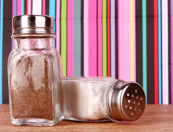 Sůl a pepř třepačky na pozadí barevných linek — Stock fotografie