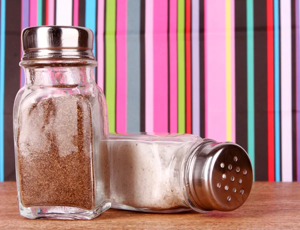 Zout en peper schudbeker op kleur lijnen achtergrond — Stockfoto