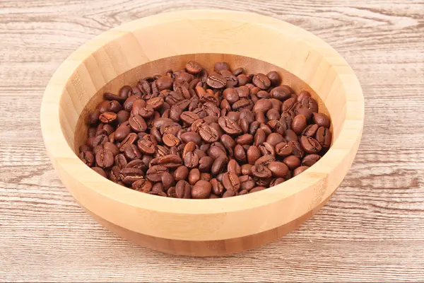 Tallrik med kaffebönor på träbord — Stockfoto