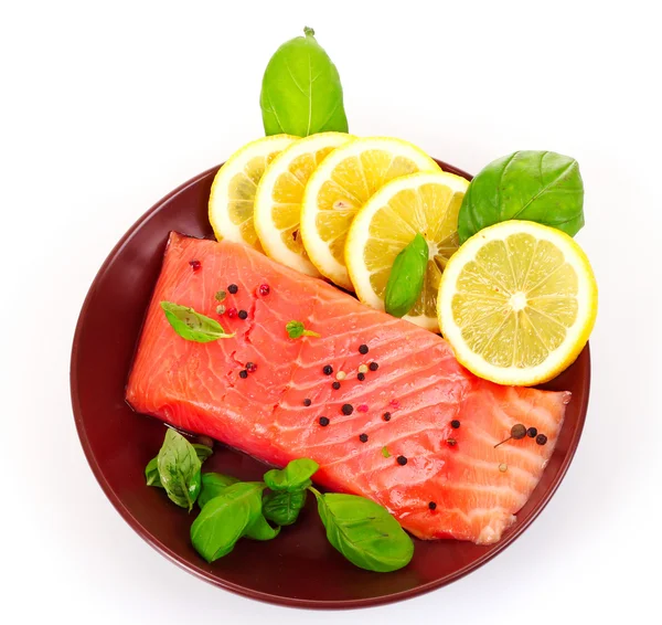 Красная рыба на тарелке с перцем и зелеными листьями — стоковое фото