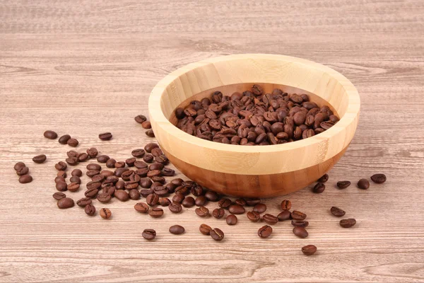 Plate with coffee beans on wooden table — Stock Photo, Image