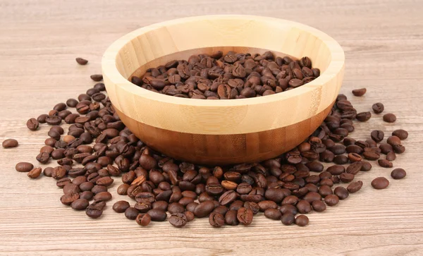 Placa com grãos de café na mesa de madeira — Fotografia de Stock