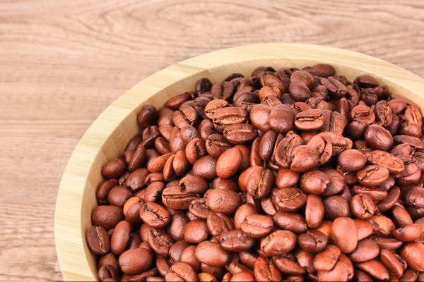 Placa con granos de café sobre mesa de madera — Foto de Stock